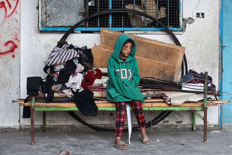 A Palestinian girl looks on as others clear debris from a makeshift displacement tent camp which was hit by Israeli strikes last week at the UNRWA-run Abou Helou school for girls in the central Gaza Strip. Photo: Eyad Baba/AFP via Getty Images