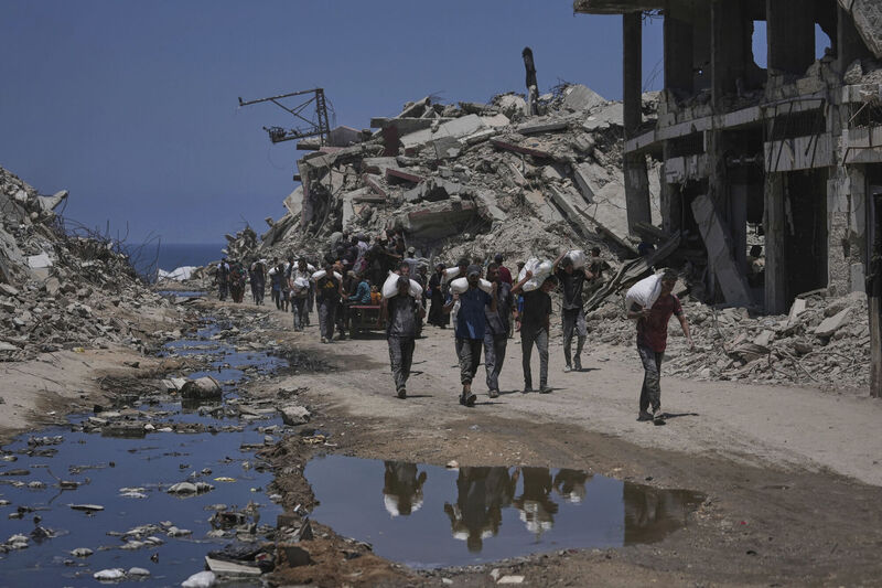 Palestinians carry sacks of flour unloaded from a humanitarian aid convoy that reached Gaza City from the northern Gaza Strip on Tuesday. Photo: AP/Jehad Alshrafi