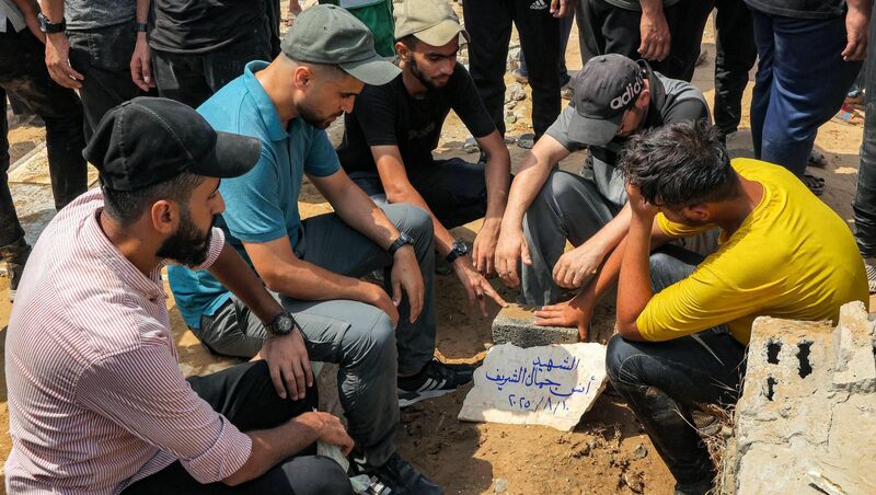 Mourners sit around the grave of Al Jazeera correspondent Anas al-Sharif, who was killed alongside other journalists in an overnight Israeli strike on their tent in Gaza City. Picture: Omar Al-qatta/AFP