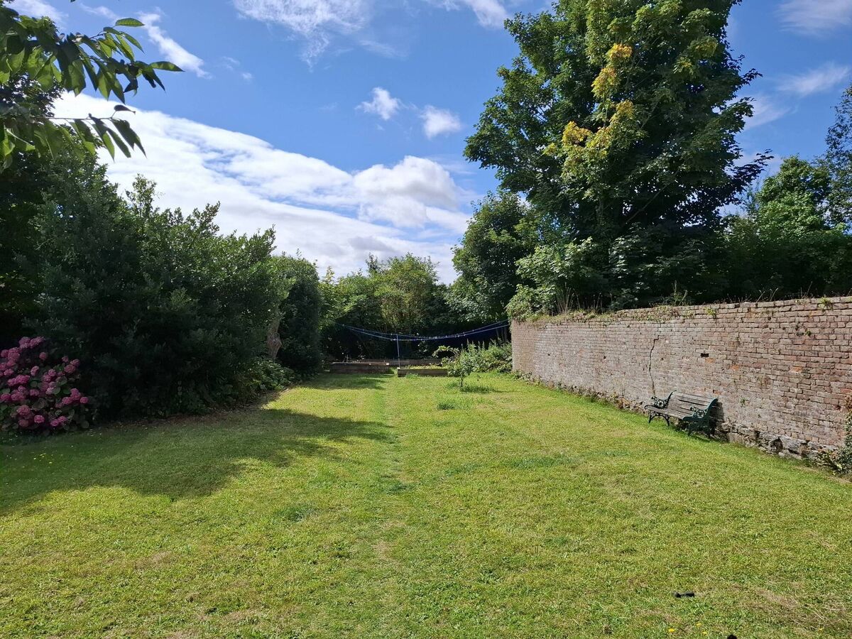 Long stretch of lawn forms the stem of the 'T', with  redbrick orchard wall to the right
