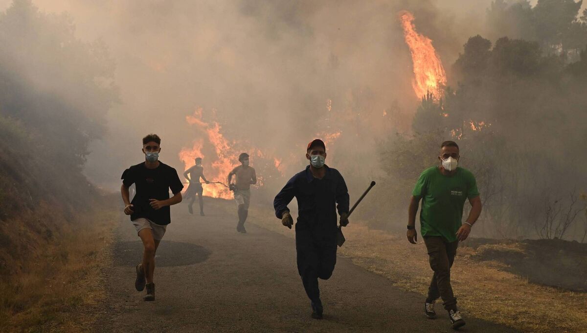 People run by a burnt area during a wildfire near the village of Larouco, in the province of Ourense, Spain, on Wednesday. Picture: Miguel Riopa/AFP