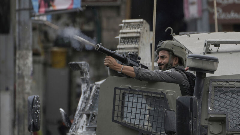 A member of Israeli security forces fires tear gas during a military raid in the West Bank city of Nablus on Wednesday. Picture: Majdi Mohammed/AP A member of Israeli security forces fires tear gas during a military raid in the West Bank city of Nablus on Wednesday. Picture: Majdi Mohammed/AP