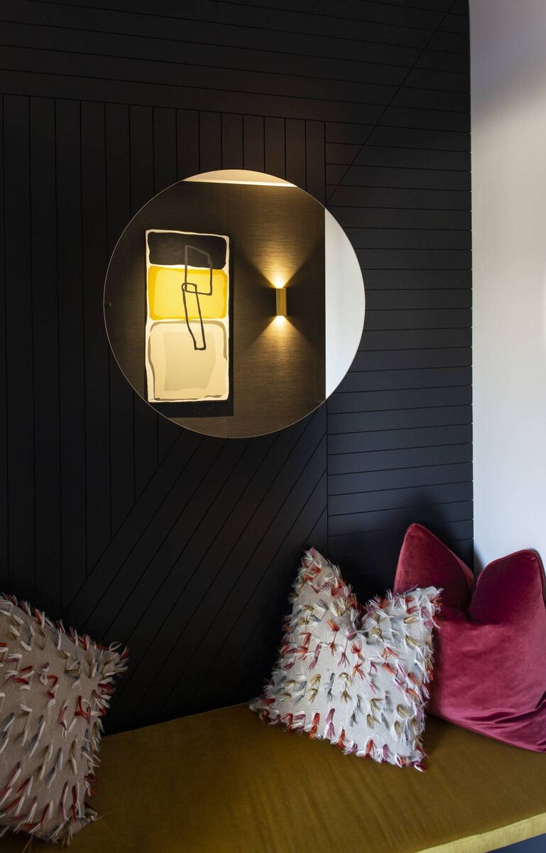 This boot room bench in the entrance hall of a new-build contemporary home in Foxrock, Dublin, is enriched with jewel coloured plush velvets and textured cushions, says interior designer Michelle Burnett, Cush Designs. Reflected in the round mirror is commissioned art tailored to the décor scheme, lit by wall lights for added ambience. Picture: Paul Sherwood 