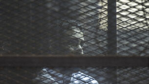 Mr Alaa Abd El-Fattah in a cage in a Cairo court in 2015 (AP)