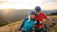 Portrait of beautiful senior couple on bike ride in autumn nature. Checking performance and route on smartwatch.