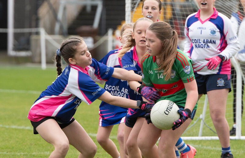 Grace Ni Airtneada of Gaelscoil Mhuscrai holds onto the ball while being challenged by Scoil Aban Naofa's Caoimhe Ni Cheallaigh. Pic: Howard Crowdy. Grace Ni Airtneada of Gaelscoil Mhuscrai holds onto the ball while being challenged by Scoil Aban Naofa's Caoimhe Ni Cheallaigh. Pic: Howard Crowdy.