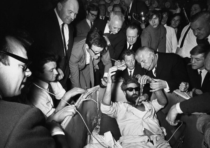 A bearded Mick Meaney, wearing dark glasses after two months in darkness, being examined by a doctor at the Admiral Nelson pub in London, on April 22, 1968, after his 61 days buried alive. Picture: Peter Kemp/AP
