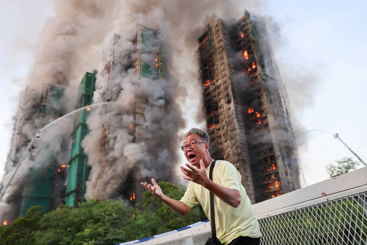 A man reacts, as smoke rises while flames engulf bamboo scaffolding across multiple buildings at Wang Fuk Court housing estate, in Tai Po, Hong Kong, China, November 26, 2025. REUTERS/Tyrone Siu TPX IMAGES OF THE DAY A man reacts, as smoke rises while flames engulf bamboo scaffolding across multiple buildings at Wang Fuk Court housing estate, in Tai Po, Hong Kong, China, November 26, 2025. REUTERS/Tyrone Siu TPX IMAGES OF THE DAY