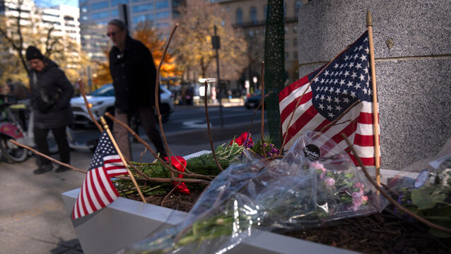 <p>People walk past a small memorial in a planter where two National Guard members were shot in Washington. (Mark Schiefelbein/AP)</p>
