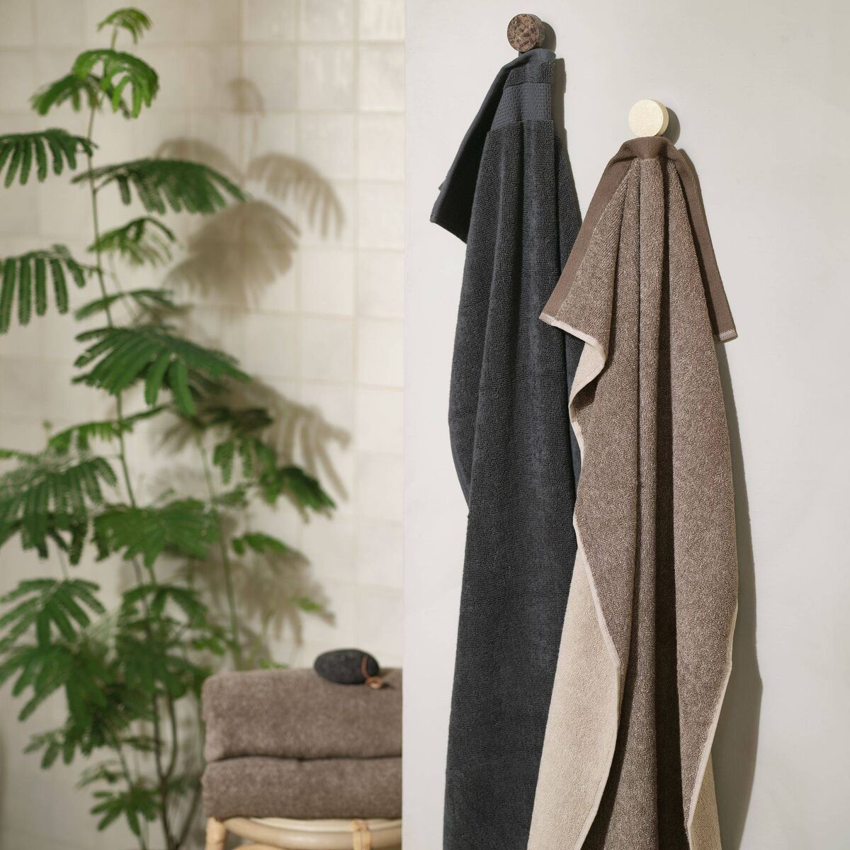 Clean towels and plant life give texture to what can be clinical surroundings in the bathroom. Picture: Jysk