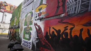 <p>A man walks past a mural related to the 2026 FIFA World Cup in Mexico City on December 5, 2025.  (Photo by Alfredo ESTRELLA / AFP via Getty Images)</p>