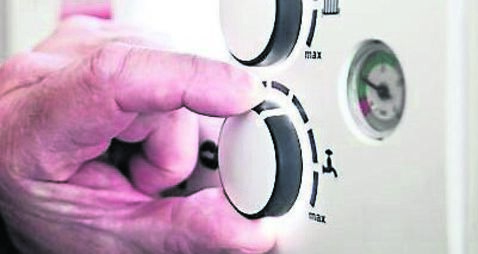 A pensioner adjusting the temperature control on his combi boiler. Redcar, UK. 26/5/2021. Photograph: Stuart Boulton.