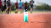 Close up Energy drink bottle on the Running track with blurred athlete  background