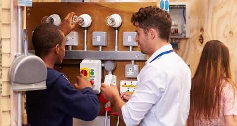 Teacher Helping Students Training To Be Electricians