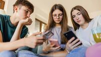Group of three teenagers are using mobile phones in a living room