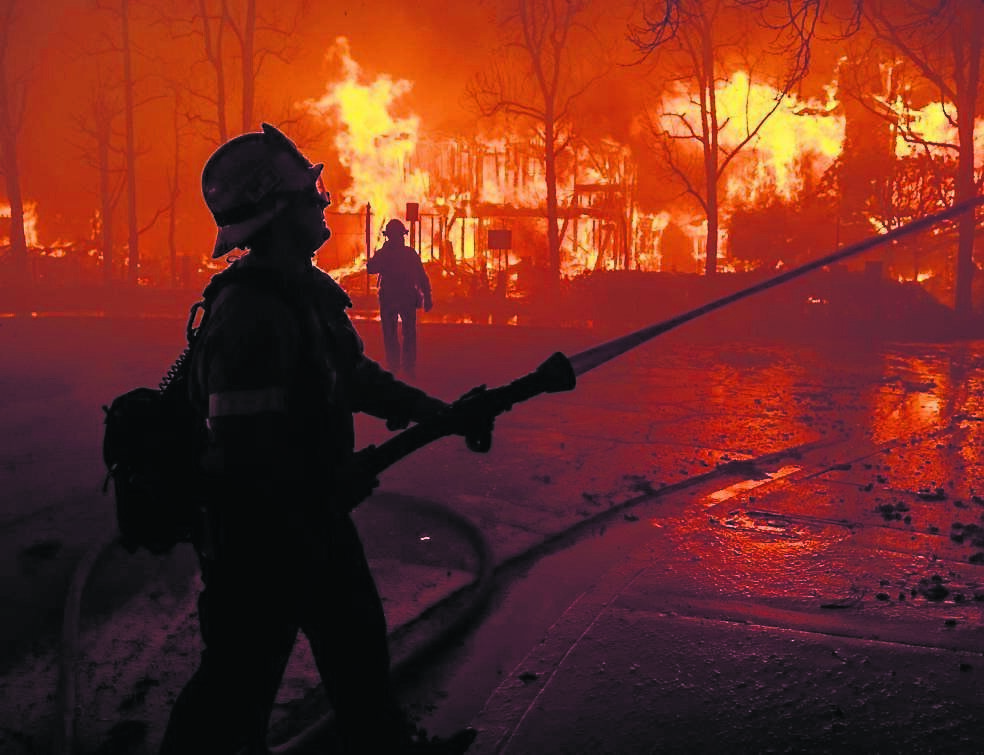 Firefighters battle the Eaton Fire in strong winds as homes burn on January 7, 2025 in Pasadena, California. Picture: David McNew/Getty
                    