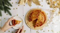 Woman's hands take a piece of royal galette from a saucer on the table.