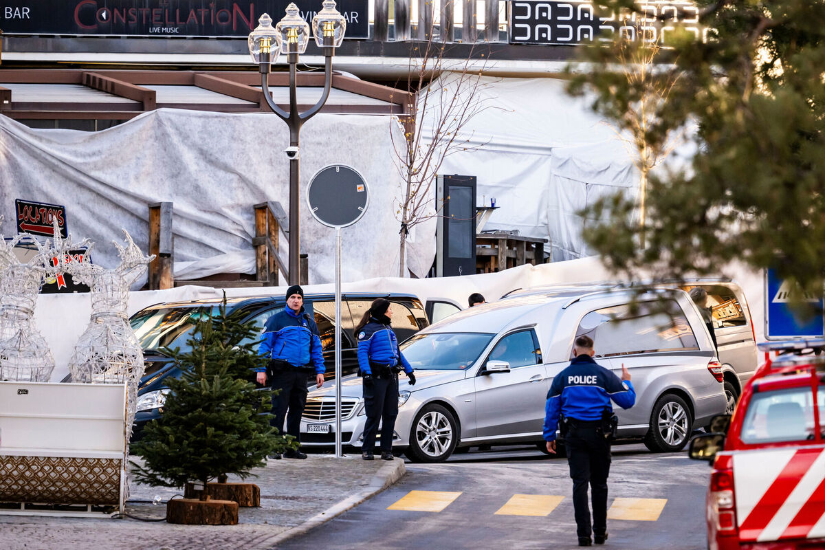 A hearse car drives as police officers inspect the area where a fire broke out at the Le Constellation bar and lounge during New Year's celebration, in Crans-Montana, Switzerland, Thursday, January 1, 2026. (Jean-Christophe Bott/Keystone via AP) A hearse car drives as police officers inspect the area where a fire broke out at the Le Constellation bar and lounge during New Year's celebration, in Crans-Montana, Switzerland, Thursday, January 1, 2026. (Jean-Christophe Bott/Keystone via AP)