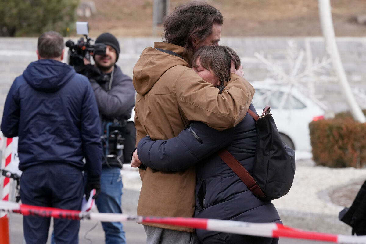 People mourn near the sealed off Le Constellation bar, where a devastating fire left dead and injured during the New Year's celebrations in Crans-Montana, Swiss Alps, Switzerland, Friday, Jan. 2, 2026. (AP Photo/ Antonio Calanni)