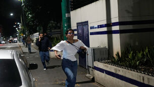 Pedestrians run after explosions and low-flying aircraft were heard in Caracas on Saturday (Matias Delacroix/AP) Pedestrians run after explosions and low-flying aircraft were heard in Caracas on Saturday (Matias Delacroix/AP)