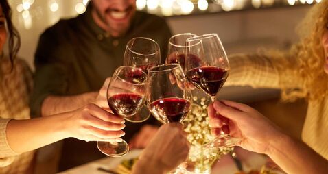 happy friends drinking red wine at christmas party