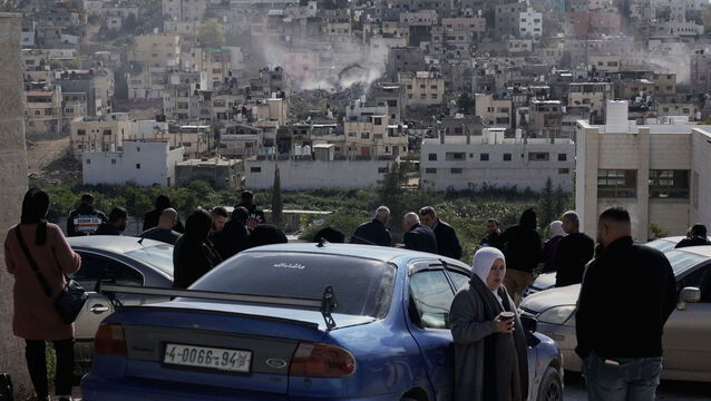<p>People watch on New Year's Eve as an Israeli army bulldozer demolishes homes in the Palestinian refugee centre of Nur Shams near the West Bank city of Tulkarem. Picture: Majdi Mohammed/AP</p>