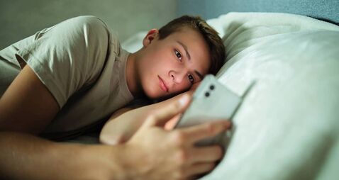 Teenager Using Cell Phone in Bed