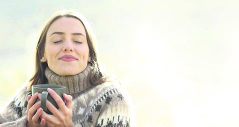 Satisfied woman drinking and relaxing in winter in a park