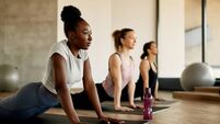 iStock-1339701353.jpg Black female athlete doing stretching exercises while warming up with group of women at health club.