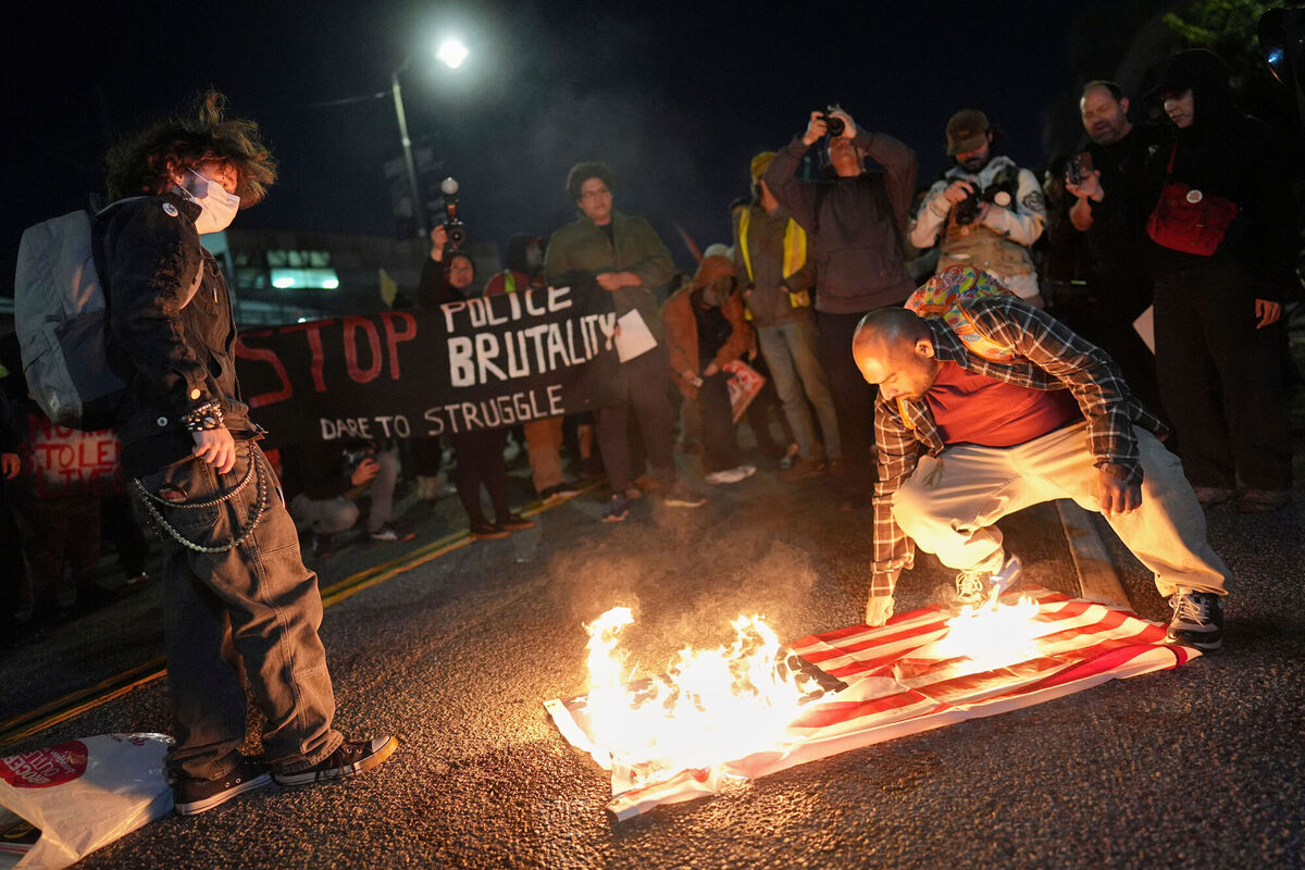 A protester burns an American flag in front of the Metropolitan Detention Center for the Federal Bureau of Prisons during a protest in Los Angeles on Thursday following the death of Renee Good, who was fatally shot by an ICE officer. Photo: AP/Jae C. Hong