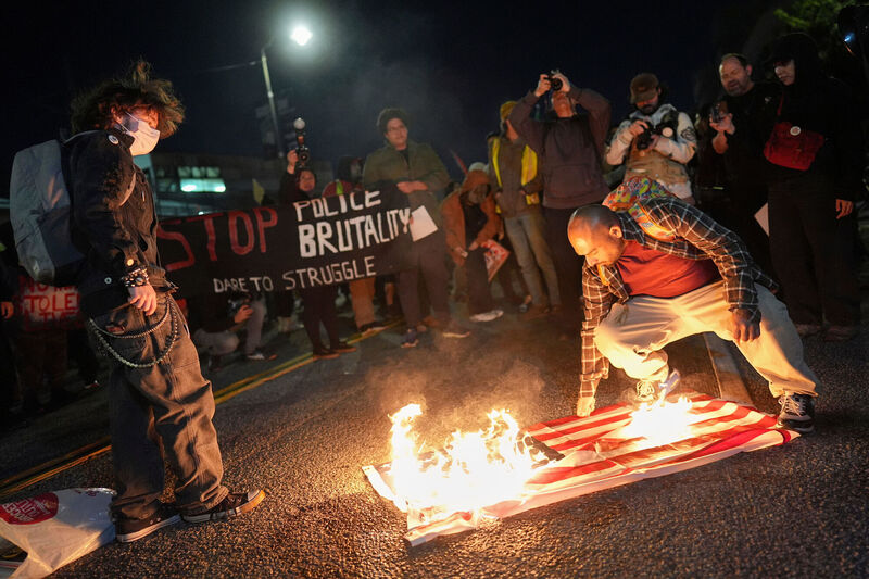 A protester burns an American flag in front of the Metropolitan Detention Center for the Federal Bureau of Prisons during a protest in Los Angeles on Thursday following the death of Renee Good, who was fatally shot by an ICE officer. Photo: AP/Jae C. Hong