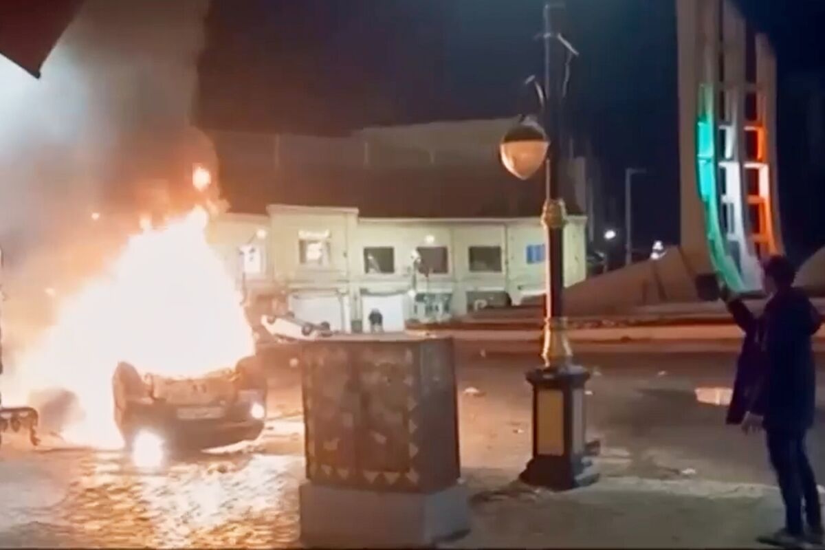 This frame grab from a video released Friday, Jan. 9, 2026, by Iranian state television shows a man holding a device to document burning vehicles during a night of mass protests in Zanjan, Iran. Picture: Iranian state TV via AP