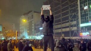 <p>In this frame grab from video obtained by the AP outside Iran, a masked demonstrator holds a picture of Iran's Crown Prince Reza Pahlavi during a protest in Tehran, Iran. (UGC via AP)</p>