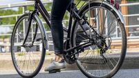 Woman rides bicycle with basket along the banks of the Seine