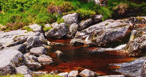 Mountain stream flows through granite boulders in Glenmacnass valley, County Wicklow, Ireland