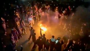 <p>A frame grab from footage circulating on social media shows protesters dancing and cheering around a bonfire (AP)</p>