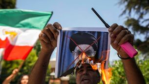 A demonstrator burns a poster of Iran’s Supreme Leader Ayatollah Ali Khamenei (Esteban Felix/AP)
