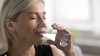 Smiling face of elderly lady having glass of cold water