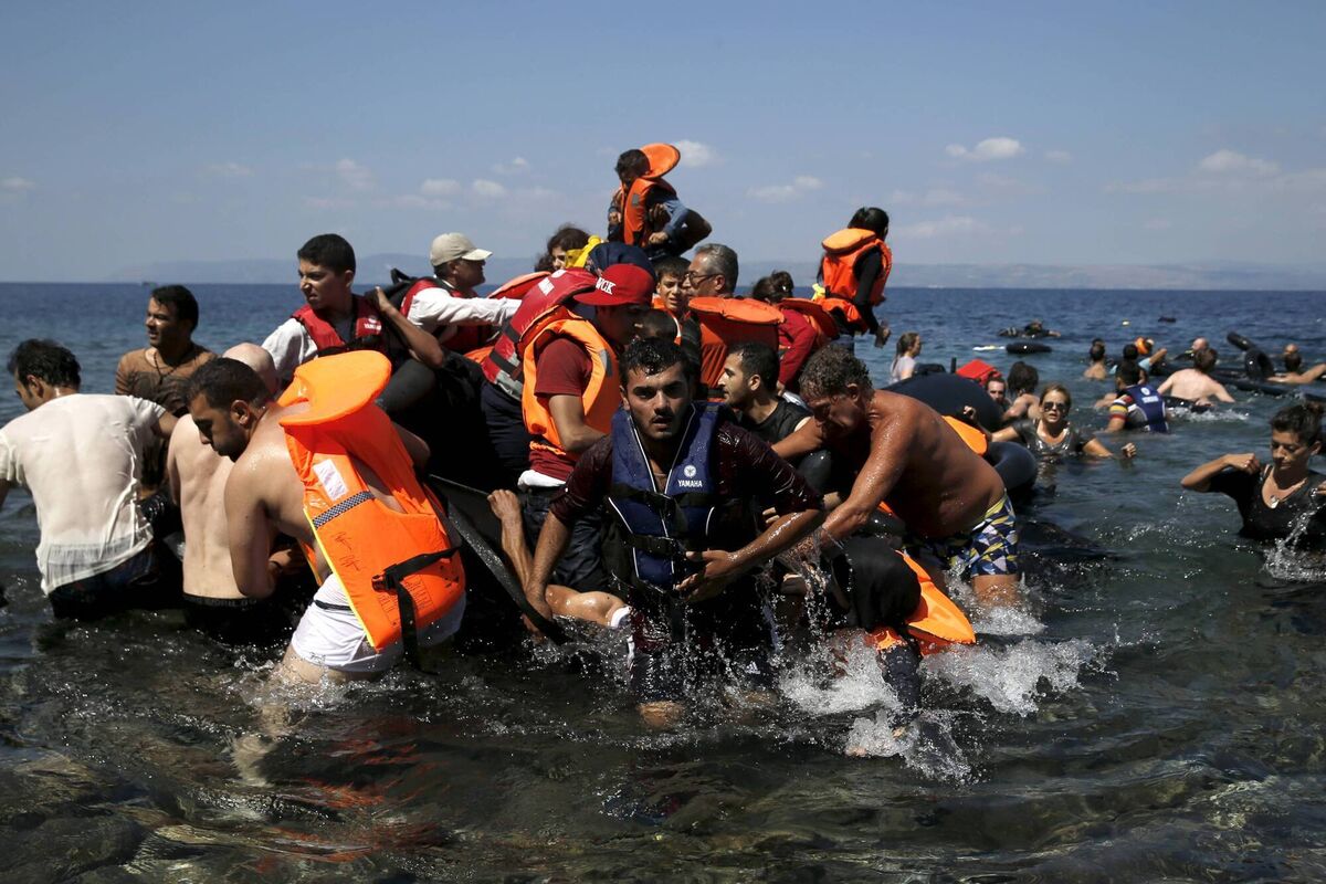 Syrian and Afghan refugees are helped by locals after their dinghy deflated some 100m away from Lesvos, in 2015.	Picture: Alkis Konstantinidis/Reuters
                    