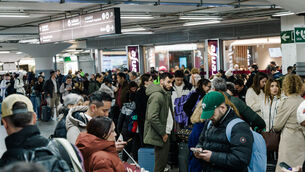 Passengers wait in the hall of Madrid train station on Sunday (Carlos Lujan/AP)