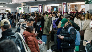 <p>Passengers wait in the hall of Madrid train station on Sunday. Picture: Carlos Lujan/AP</p>