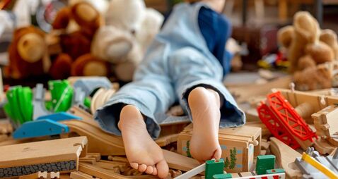 Child, cute boy, playing with toys in a playroom, focus on his feet
