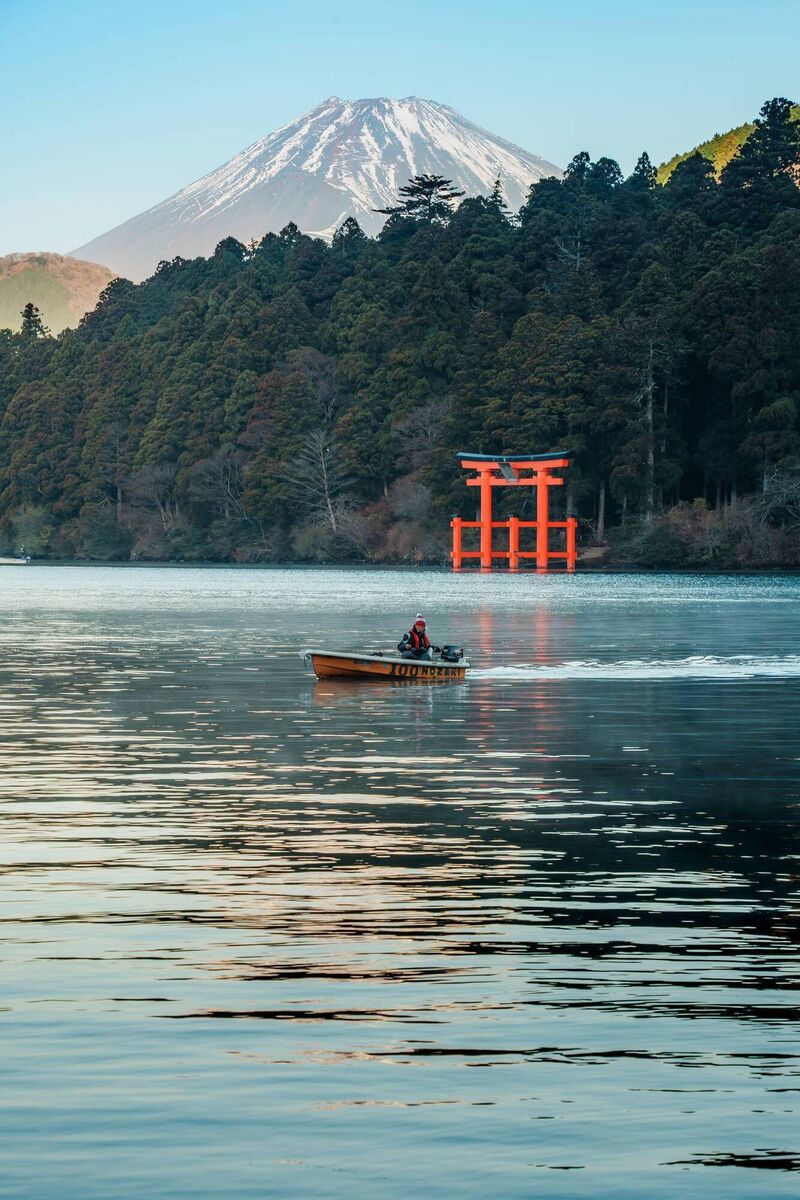 Early morning boat ride on Lake Ashi with Mount Fuji and iconic torii gate framed by dense forest in Hakone, Japan. Early morning boat ride on Lake Ashi with Mount Fuji and iconic torii gate framed by dense forest in Hakone, Japan.