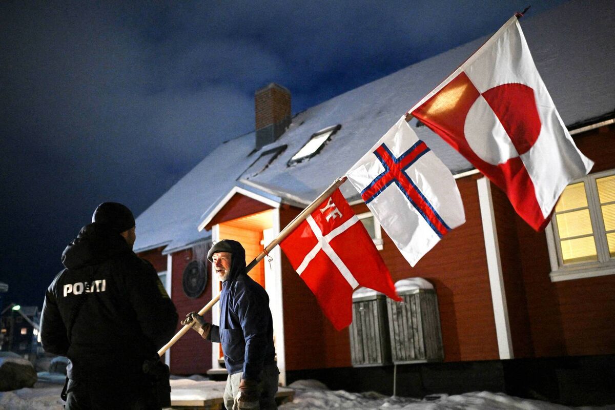 Jens Kjeldsen chats with a police officer outside the US consulate in Nuuk. Carrying the flags of Greenland and the Faroe Islands and the Danish maritime ensign, the 70-year-old carpenter and former judge is taking part in daily protests against the US administration’s bid to take over the Arctic island.	Picture: Jonathan Nackstrand/AFP/Getty
                    