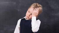 schoolgirl with headache stands at the blackboard
