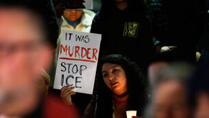 A demonstrator holds a sign during a candlelight vigil during a protest in response to the fatal shooting of 37-year-old Alex Pretti in Minneapolis (Caroline Brehman/AP)