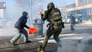 <p>A federal agent points a weapon at a protester in Minneapolis. Picture: Brandon Bell/Getty Images</p>
