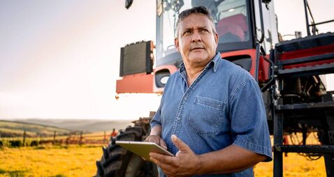 Portrait of an agronomist with a tablet in front of the agricultural machine