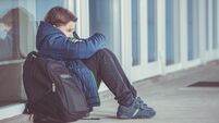 Little boy or child sitting alone on floor in front of the school after suffering an act of bullying