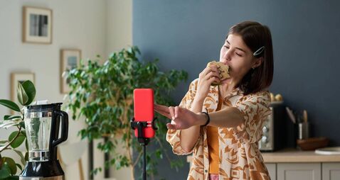 Teenage Girl Recording Video While Eating Sandwich in Kitchen